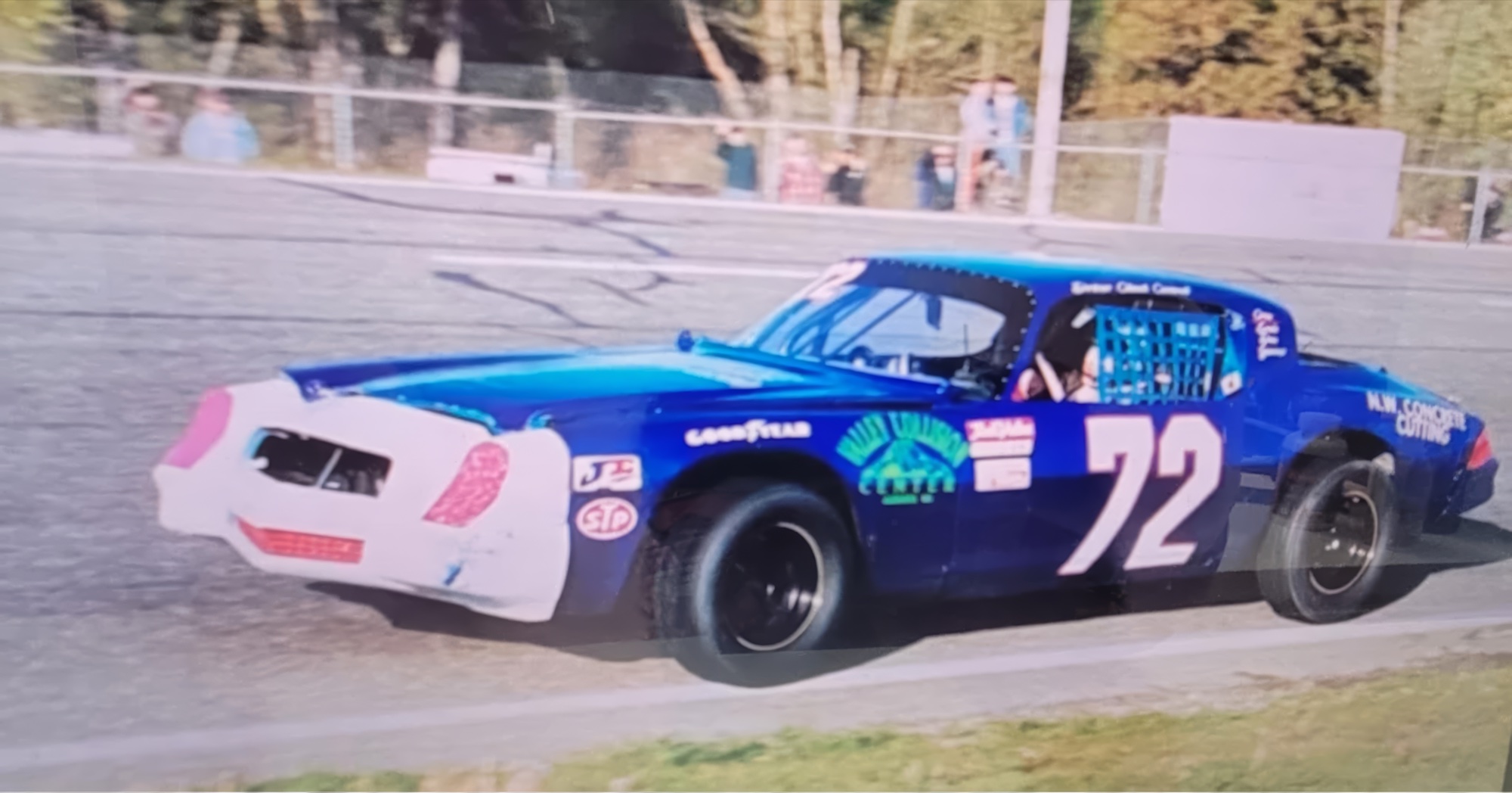 Archive photograph of the original #72 modified — blue with white front clip, Northwest Concrete Cutting and Goodyear on the fenders, mid-corner on a Northwest paved short track in the founding era.